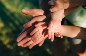foto de uma família sobrepondo duas mãos uma em cima da outra