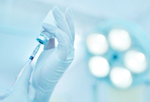 imagem de médico de luvas segurando uma dose da vacina para Covid-19