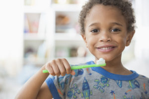criança sorrindo e segurando uma escova de dente