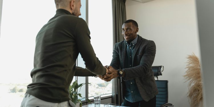 Dois homens vestidos socialmente se cumprimentando.