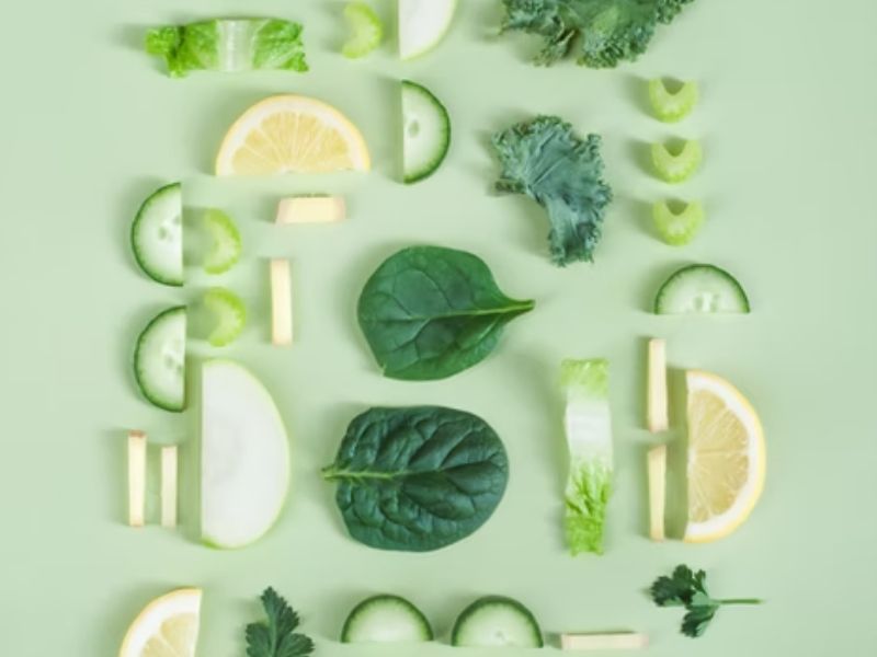 frutas e vegetais cortados em um fundo verde, representando alimentos que fazem bem para a saúde intestinal