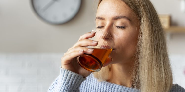 mulher bebendo kombucha vista lateral scaled