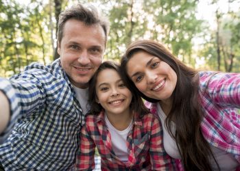familia feliz tomando selfie no parque scaled