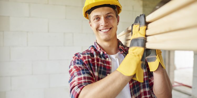 carpinteiro mais jovem segurando pranchas de madeira scaled