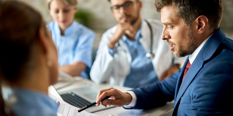 mid adult businessman healthcare workers analyzing documents during meeting office scaled