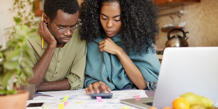 jovem casal afro americano infeliz e deprimido calculando o orcamento familiar scaled