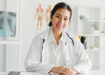 jovem medica asiatica confiante em um uniforme medico branco com estetoscopio scaled