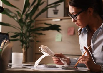 female accountant calculating tax bills while working finances office scaled
