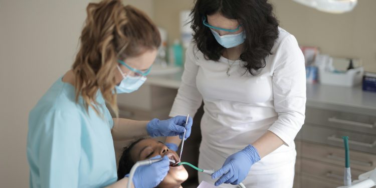 Paciente em um atendimento odontológico com duas dentistas.