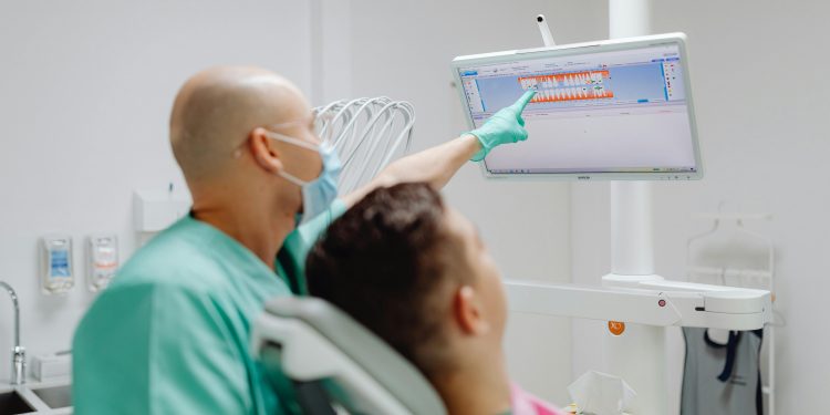 Doutor mostrando exame odontológico para paciente.