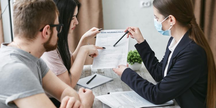 Pessoas sentadas em uma mesa, revisando contrato no papel.