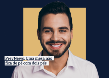 Foto: Homem branco de cabelo preto curto sorrindo e olhando pra frente com camisa social branca Frase: PrevNews: Uma mesa não fica de pé com dois pés Fundo: Fundo azul-marinho com quadrado central bege