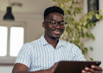 Um homem sorrindo olhando para seu tablet