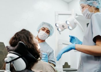 Consultório odontológico com dois dentistas e uma paciente.