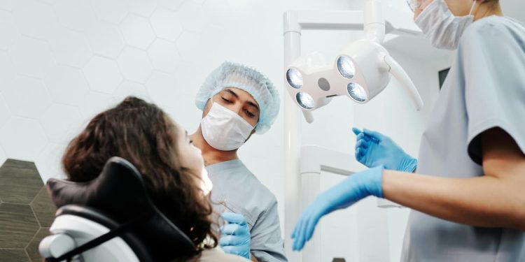 Consultório odontológico com dois dentistas e uma paciente.