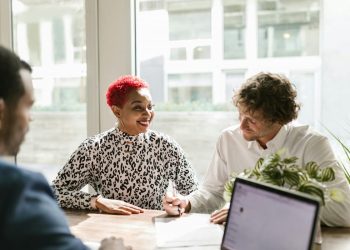Três pessoas em uma mesa assinando contrato de coparticipação.