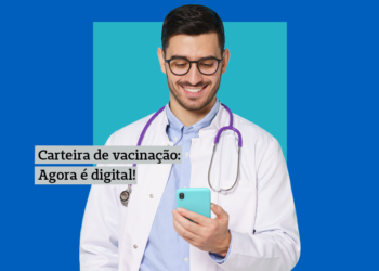 Um médico segurando um celular azul, com o texto sobre Carteira de Vacinação Digital.