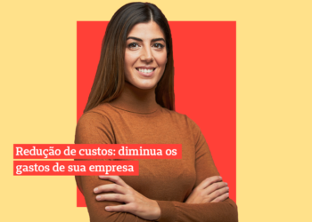 Mulher branca de cabelos lisos e castanhos olha pra câmera de braços cruzados sobre um fundo coral e amarelo.