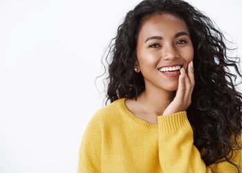 mulher com cabelos escuros e longos, colocando a mãona bochecha