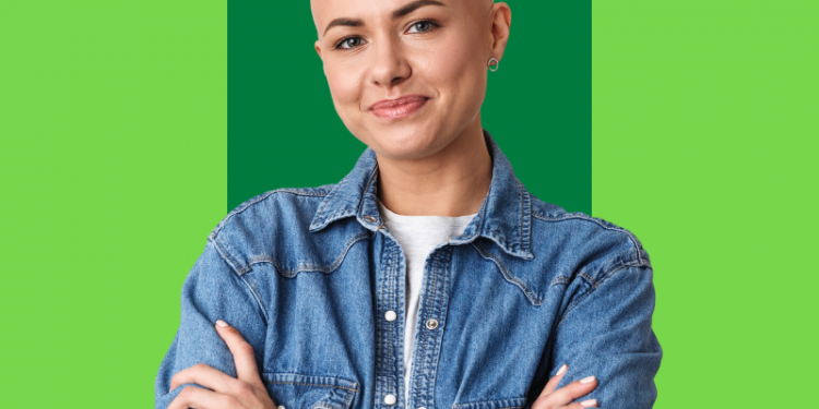 mulher careca, paciente de quimioterapia, sorrindo para a foto com os braços na frente do colo, capa do conteúdo sobre cárie de radiação
