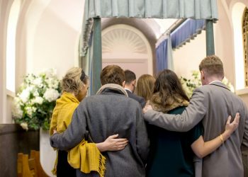 Família abraçada em um funeral.