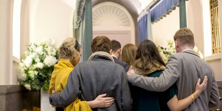 Família abraçada em um funeral.