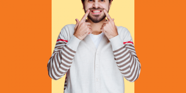 homem sorrindo com dedos apontando para a boca com um dente provisório