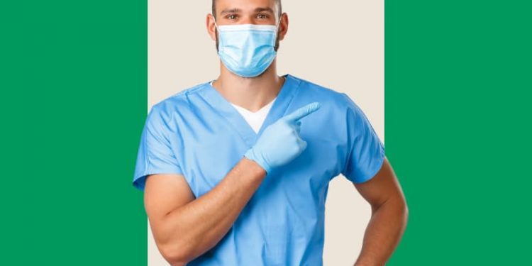 Um dentista à frente de um fundo verde e bege.