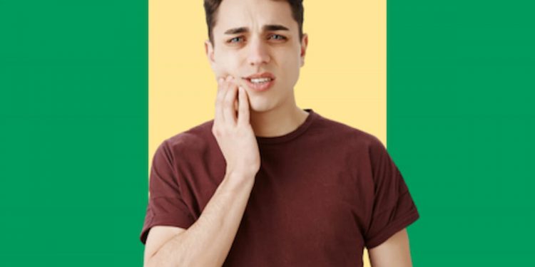 Menino com a mão em sua mandíbula com feição de dor