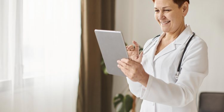 medica-do-centro-de-recuperacao-cobicoso-sorridente-idosa-com-tablet-e-estetoscopio