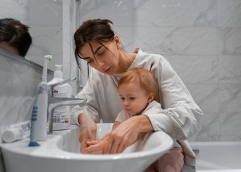 Uma mãe junto com seu filho na pia, ensinado como lavar as mãos
