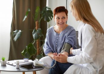 Uma médica, medindo a pressão de uma senhora