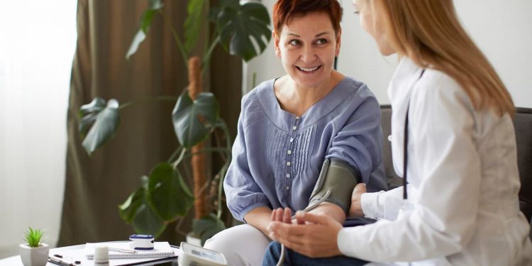 Uma médica, medindo a pressão de uma senhora