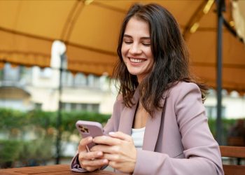 Uma mulher olhando para seu celular e sorrindo