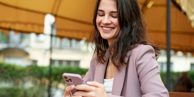 Uma mulher olhando para seu celular e sorrindo