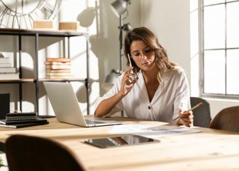 Uma mulher no celular anotando em um papel uma informação