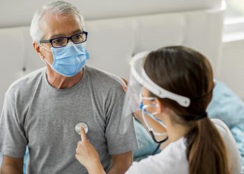 Uma médica avaliando uma paciente, ouvindo o seu coração