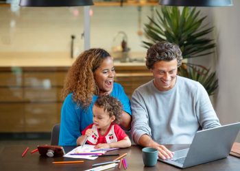 Um casal junto com sua filha, sentados olhando para o notebook