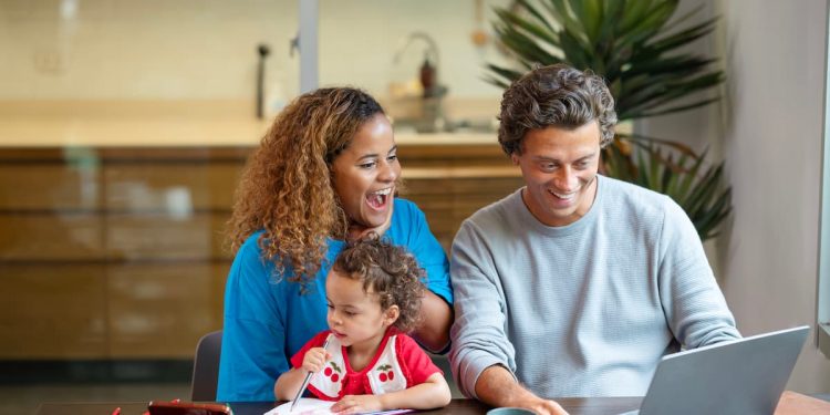 Um casal junto com sua filha, sentados olhando para o notebook