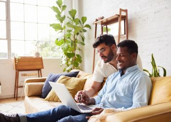 Um casal sentado na sala vendo o computador