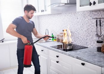Um homem apagando o fogo que está em sua panela