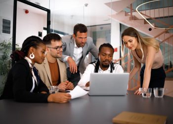 Amigos do trabalho sentados em um mesa, olhando para o computador