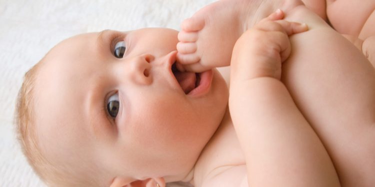 bebê com os pés na boca.