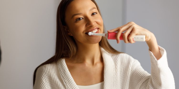 Pessoa escovando os dentes com escova elétrica