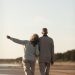 foto mostra casal na terceira idade, com homem e mulher, caminhando de braços dados