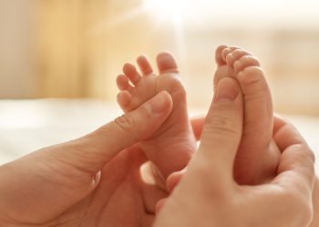 mãos de adulto segurando pés pequenos de bebê