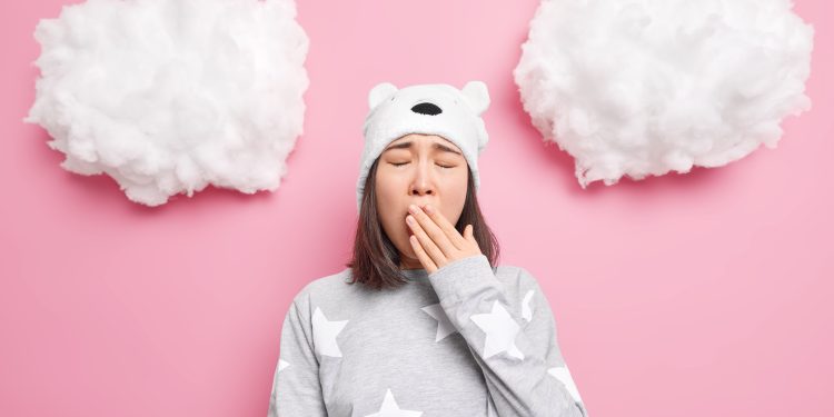 Fundo rosa com uma menina de pijama abrindo a boca e tampando-a com a mão
