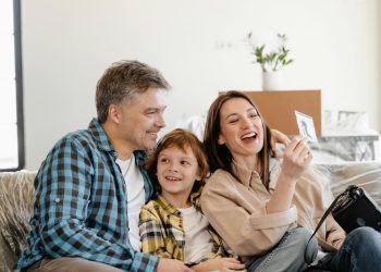 Família, pai filho e mãe, feliz se divertindo no sofá.