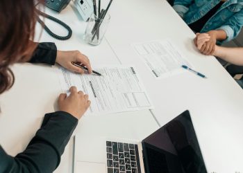 Duas pessoas em uma mesa assinando documentos.
