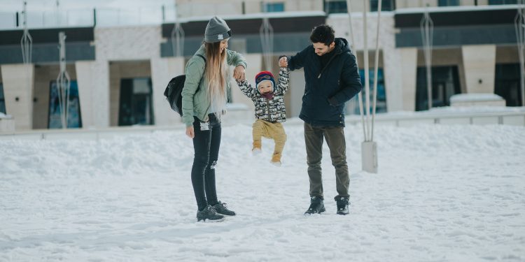 Família de mãe, filho e pai felizes na neve.